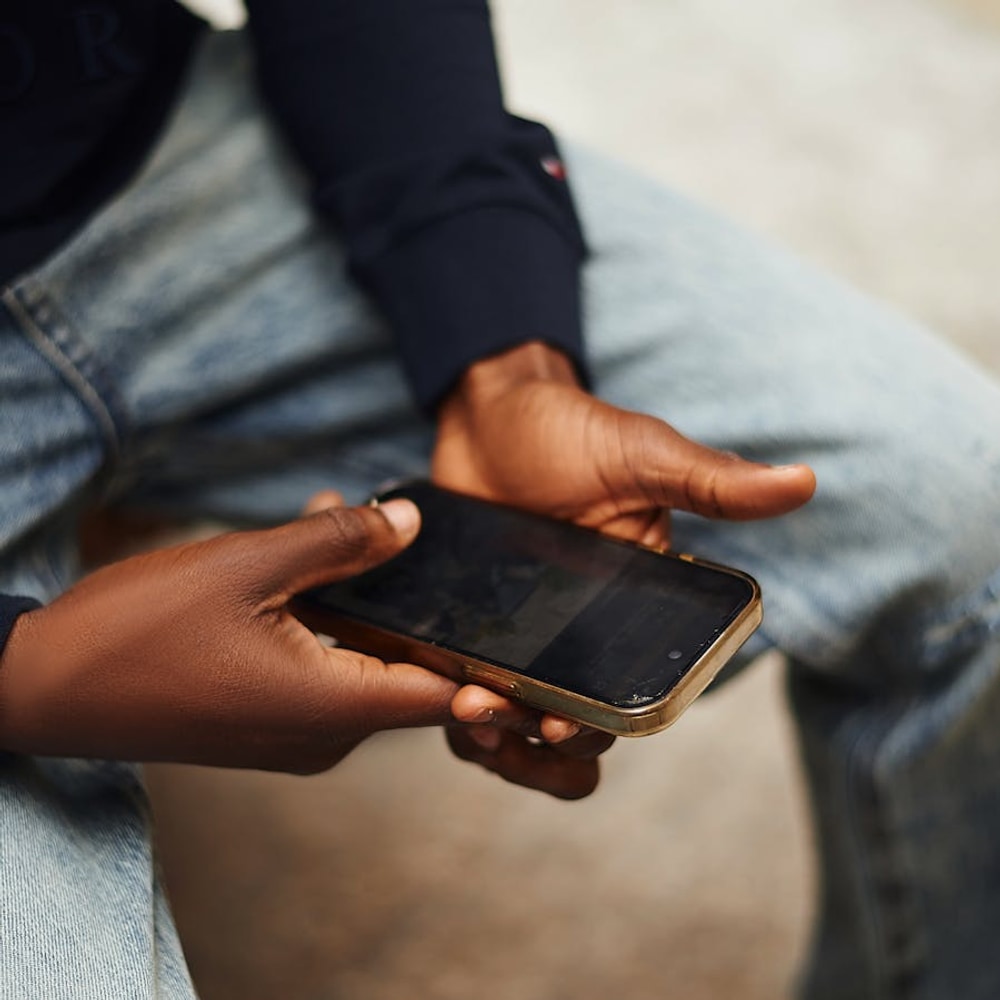 Close-up of hands holding a smartphone outdoors without showing a face