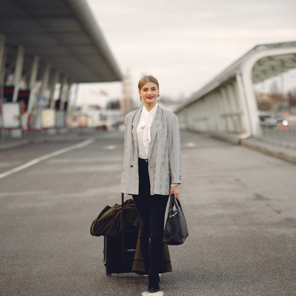 Happy female solo traveler walking through an airport terminal with rolling luggage