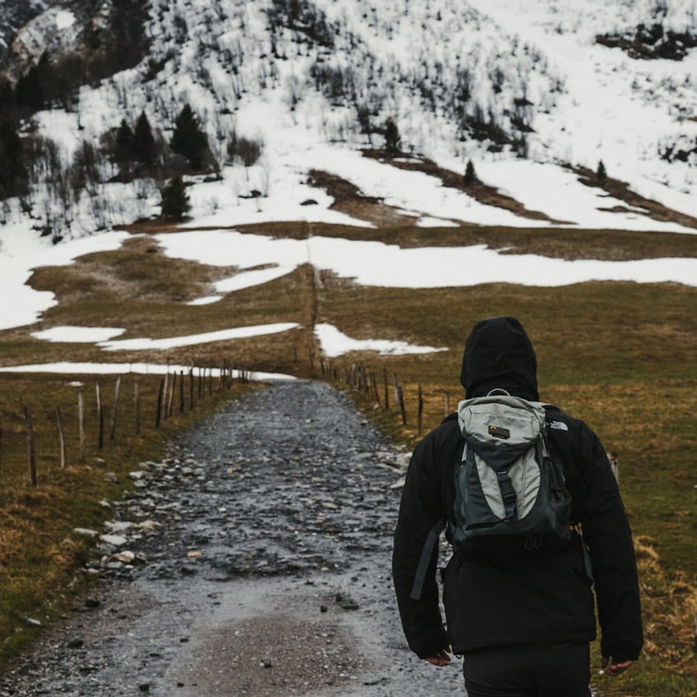 Back view of a person walking alone on an unpaved mountain path