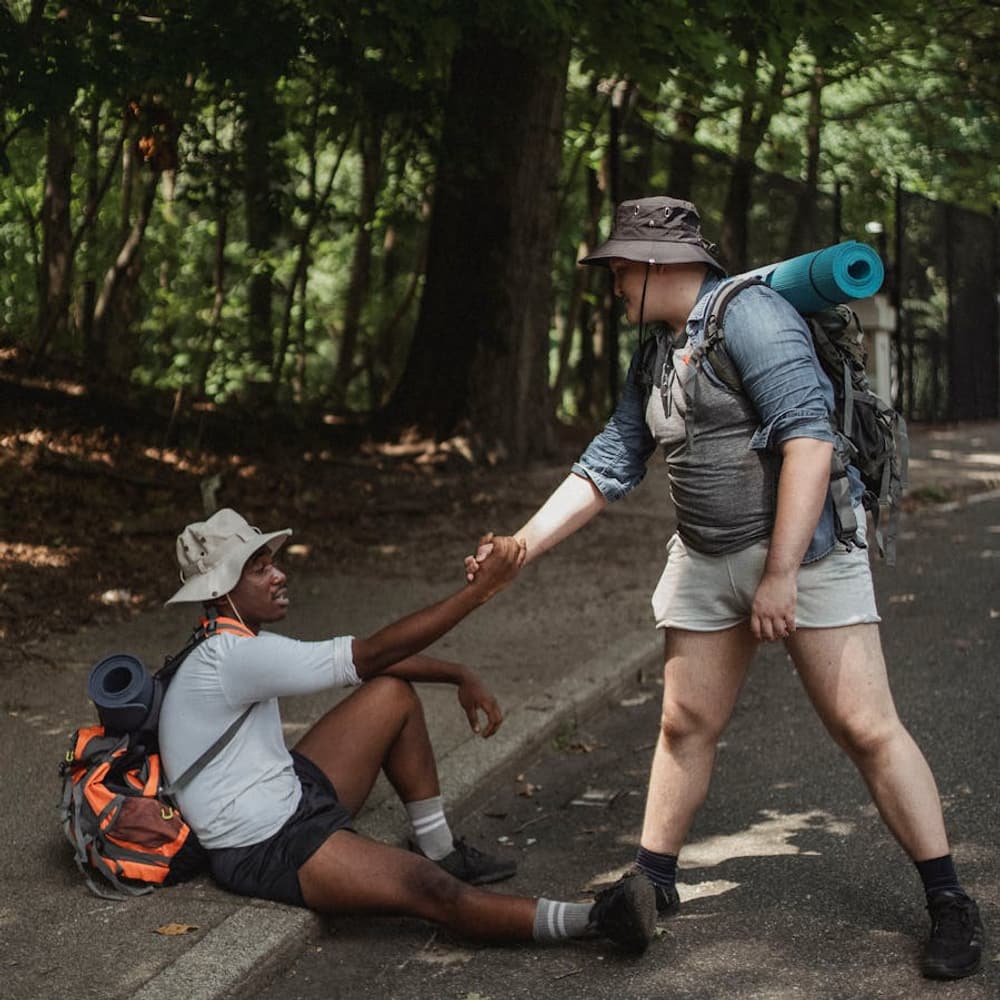 Hikers helping each other on a road viewed from behind without showing faces