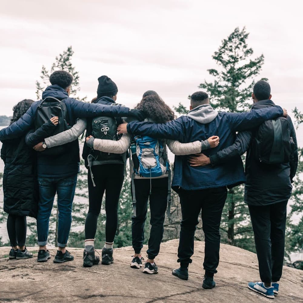 Group of friends hiking together viewed from behind on a scenic cliff trail