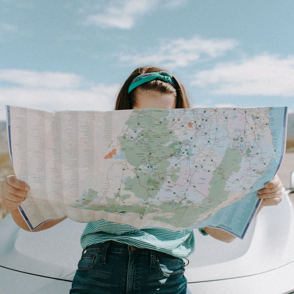 Solo female traveler studying a paper city map while navigating an urban area