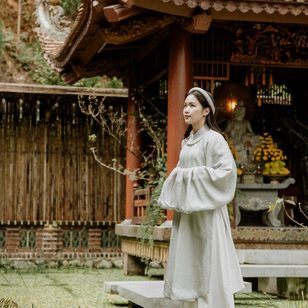 Visitor standing barefoot on stone steps at a temple garden, following local shoe customs