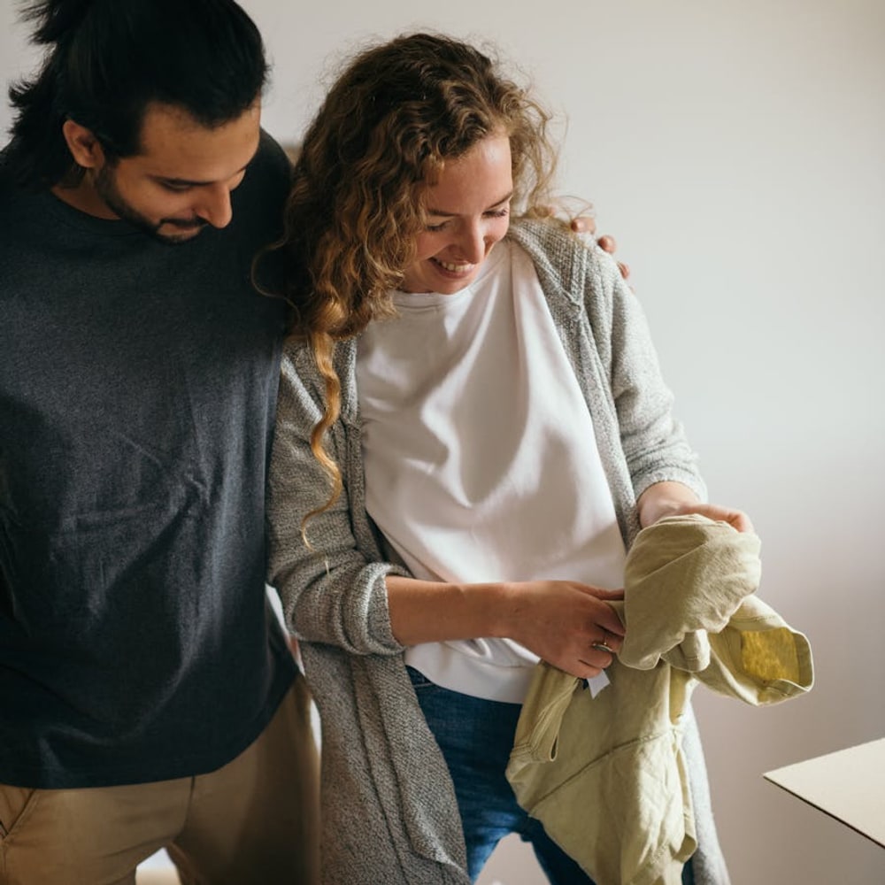 Couple packing a suitcase together with minimalist baggage in a bedroom