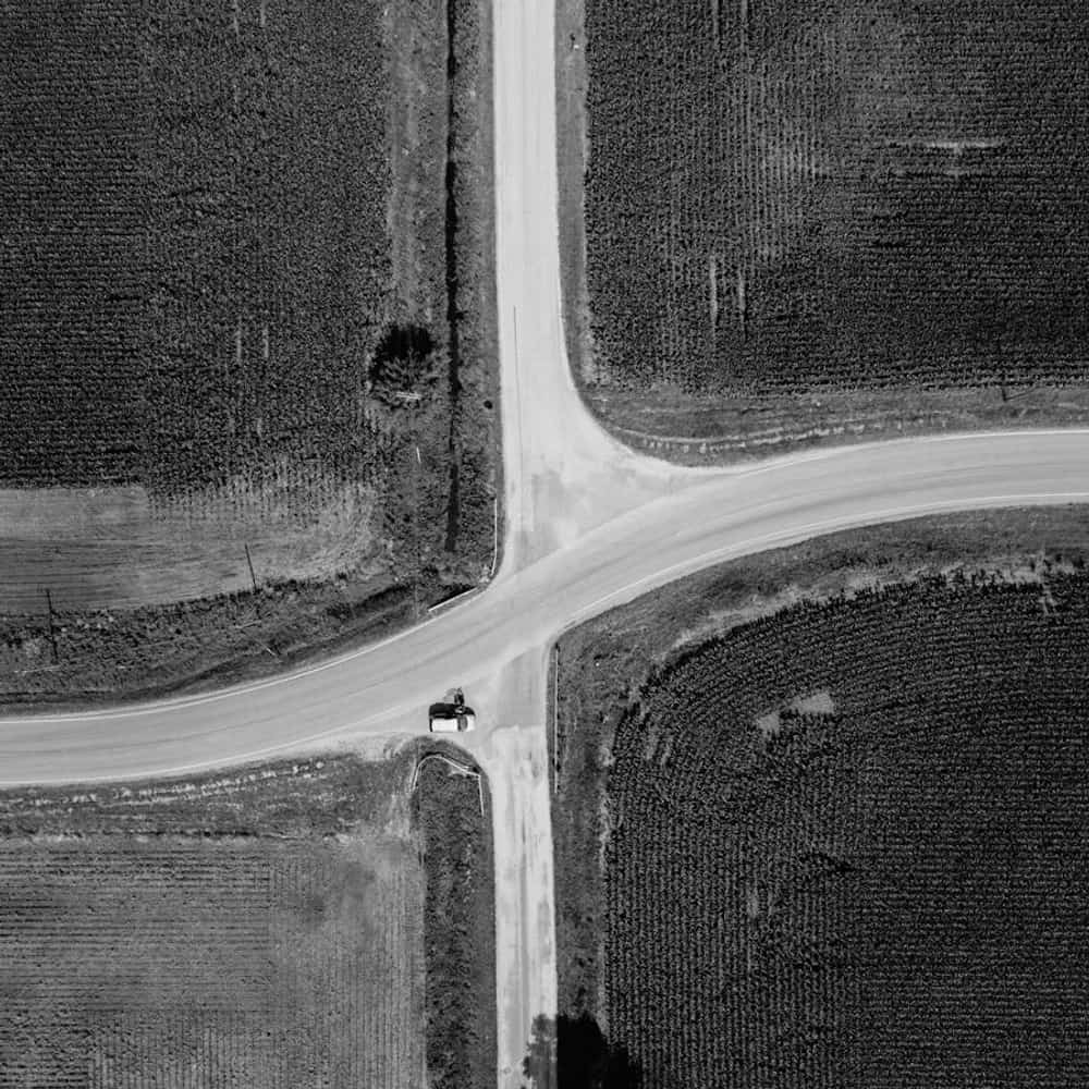 Aerial view of a car driving on a rural road through open countryside