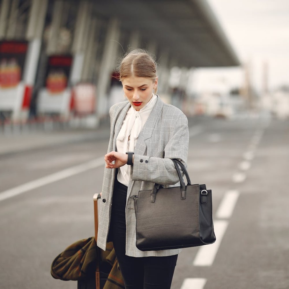 Worried young traveler hurrying through a city street with a rolling suitcase before a flight