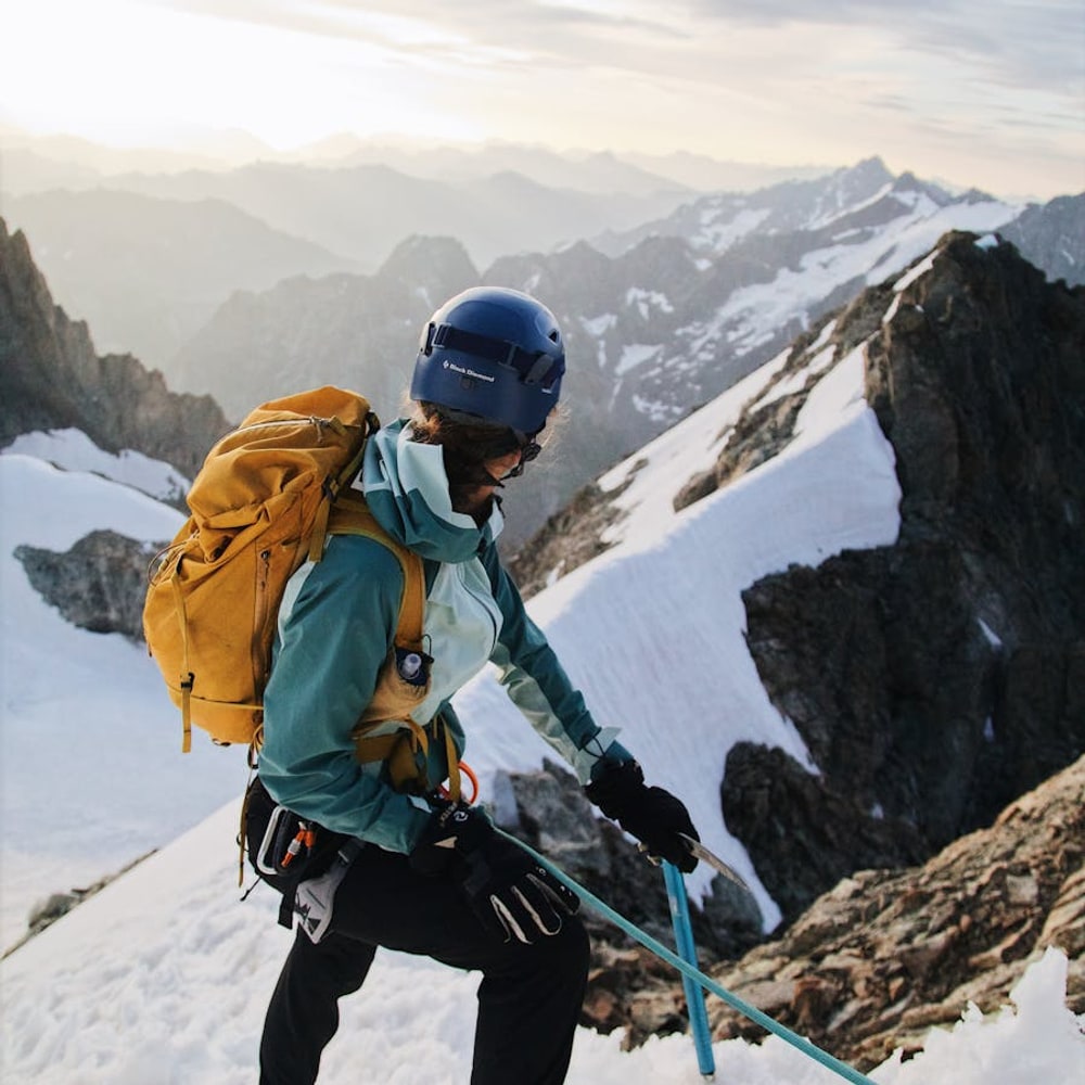 Solo hiker with backpack climbing a steep mountain trail toward open sky