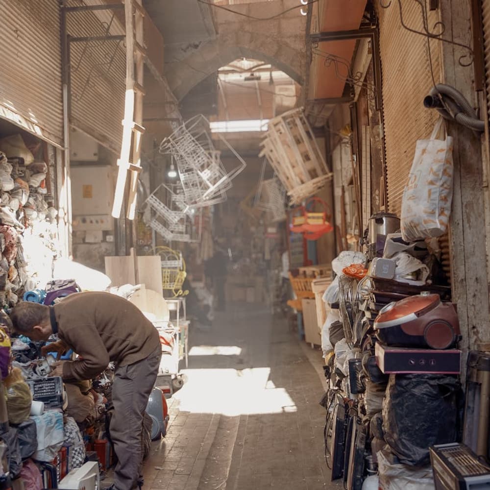 Sunlit bazaar alley lined with market stalls and shoppers in warm afternoon light