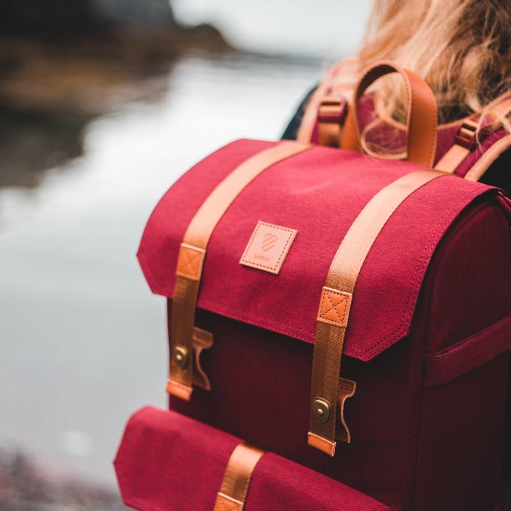 Close-up of a person carrying a compact travel backpack by the straps